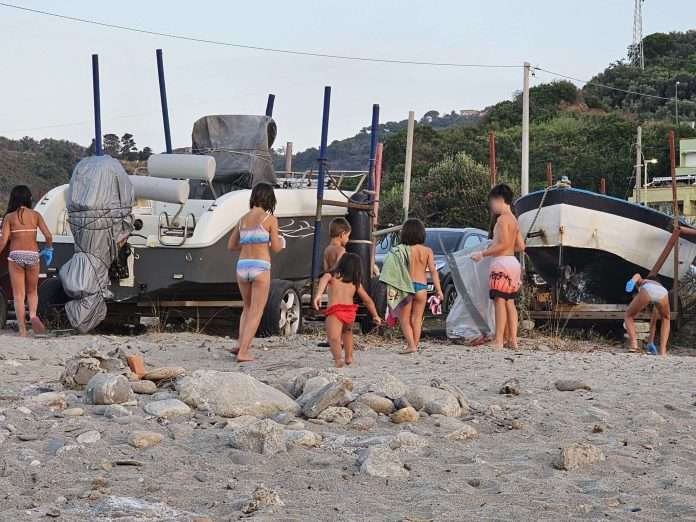 bambini collaborano alla raccolta dei rifiuti sulla costa